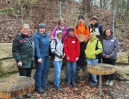 Försterin Schulz-Könicke steht mit den warm angezogenen Studierenden und 1 Lehrerin im Wald